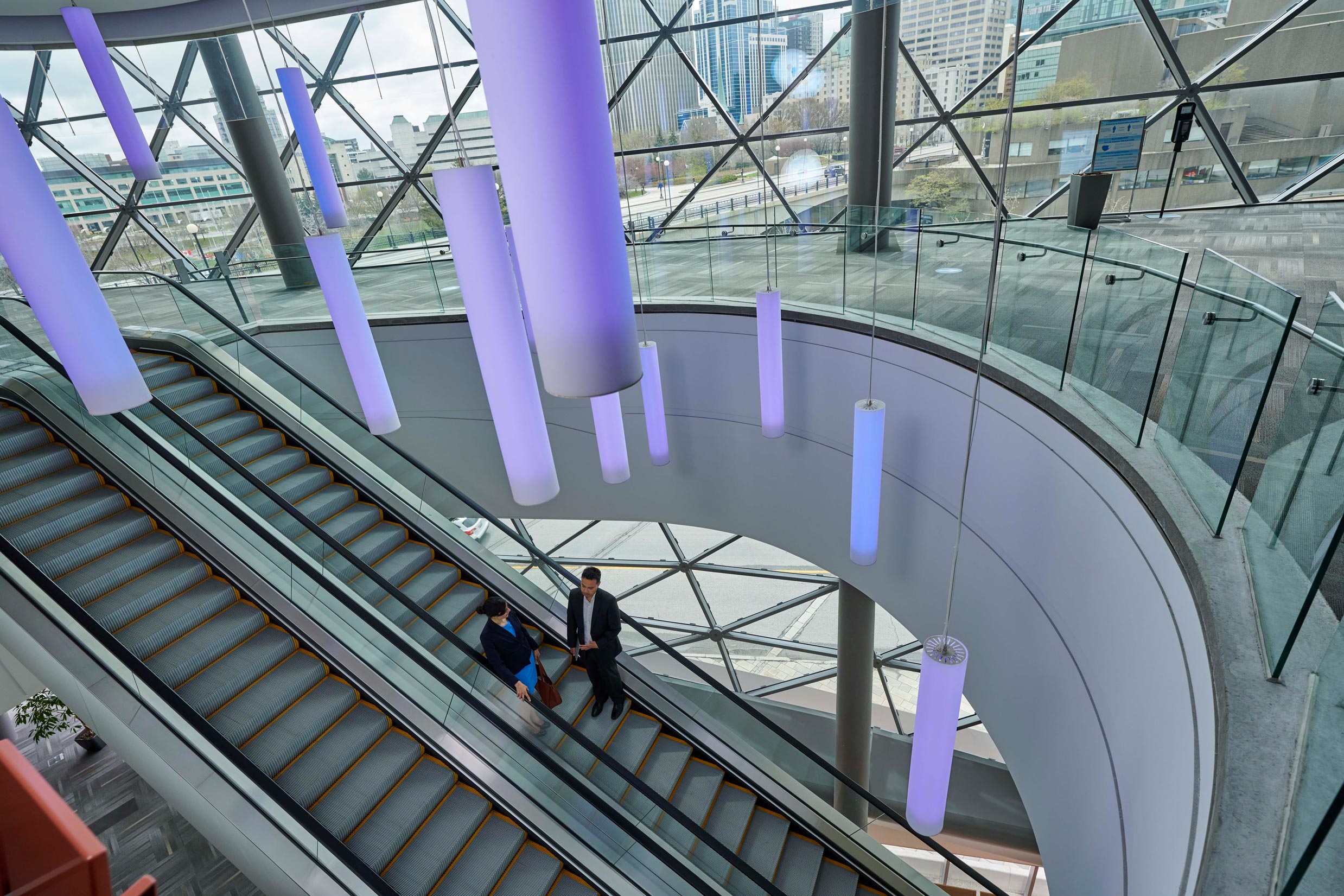 A man and woman stand on the Shaw Centre's escalators.