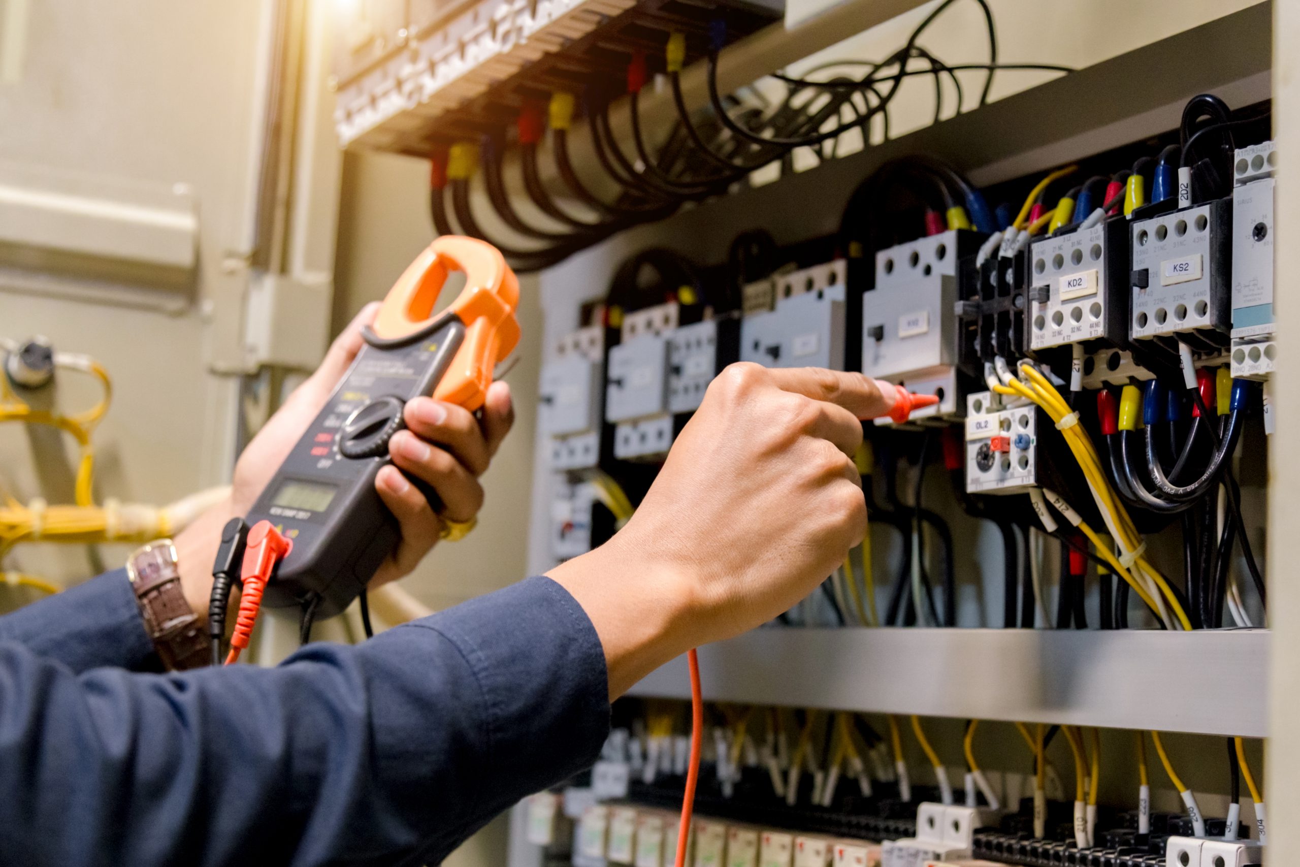 An electrician measures system voltage.