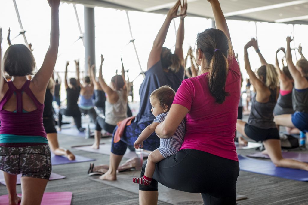 Mother holding baby while doing yoga pose in shaw centre