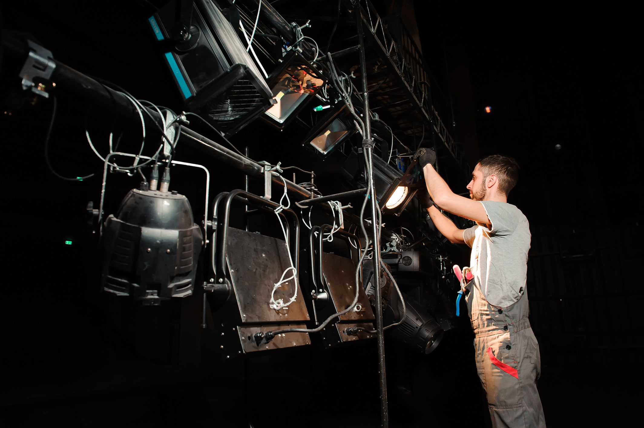 A man configures a stage lighting rig.